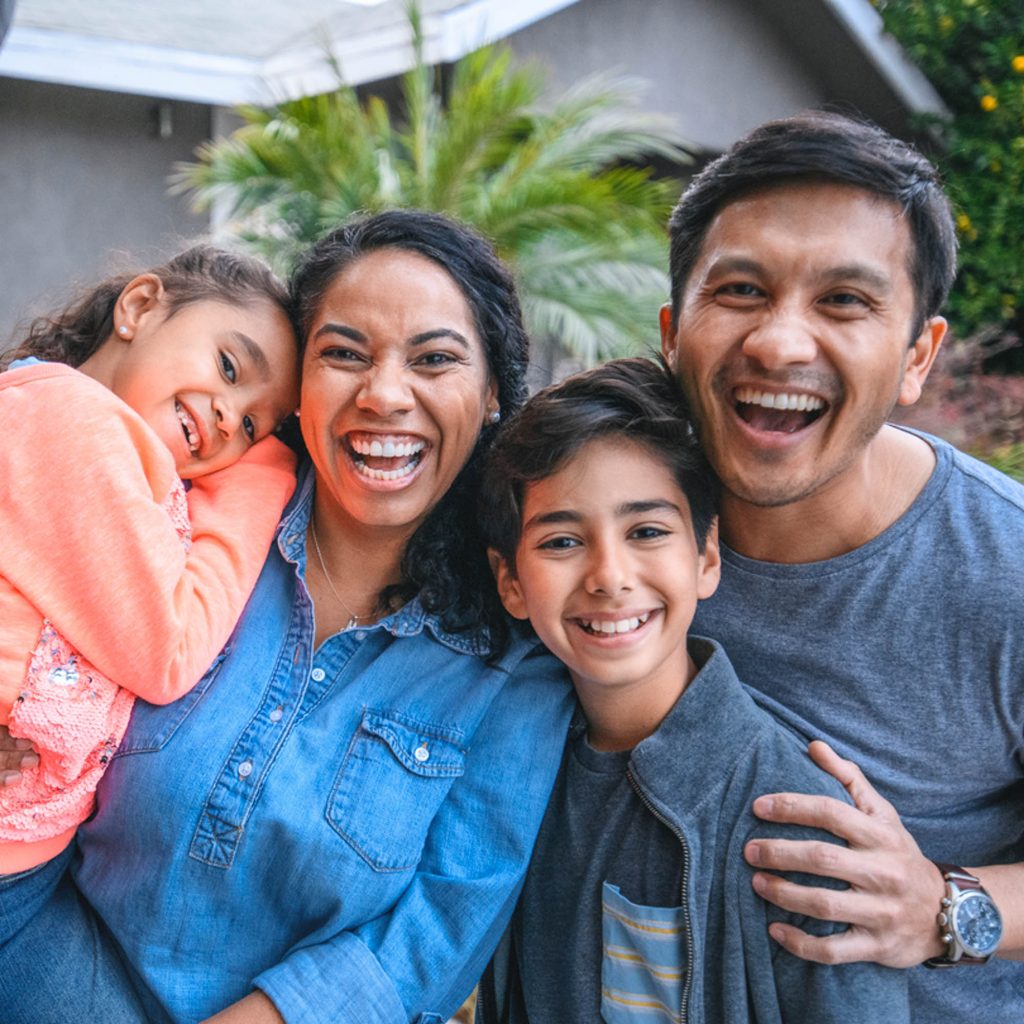 Portrait of happy family against house. Multi-ethnic parents and children are smiling on driveway. They are having fun together during weekend.